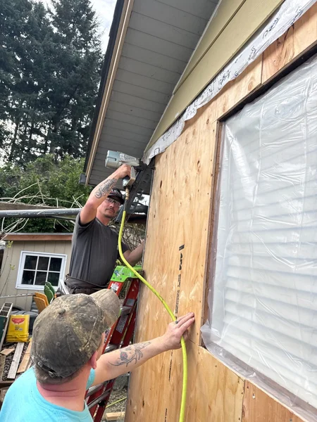 Two workers installing new wood siding on exterior wall